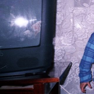Boy stands near Christmas tree with mouth open.