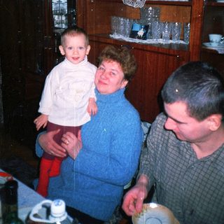 A child is held by a woman with a man nearby.