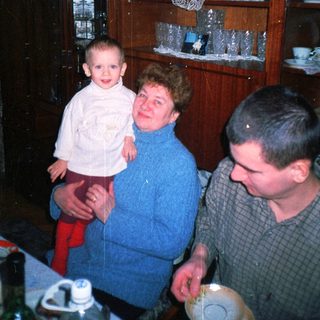 A child is held by a woman with a man nearby.