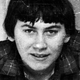 Man in plaid shirt stands near a door.