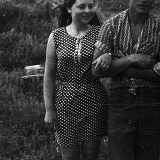 Three people stand in a field, looking directly at the camera.