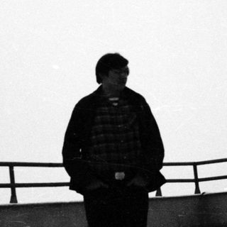 Man stands on a rooftop, looking out towards a bright sky.