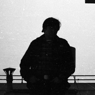 Here's a brief summary of the image: Silhouette of a person standing near a railing.