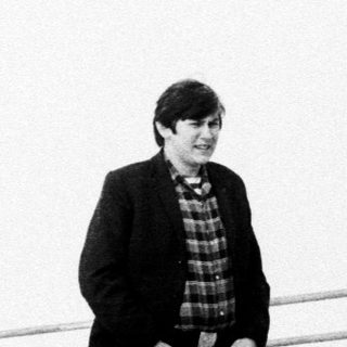 Man stands on a ledge, looking towards a cloudy sky.