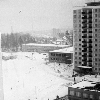 Winter scene with apartment buildings and snow-covered landscape.