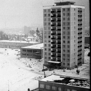 Winter scene with apartment buildings and snow-covered landscape.