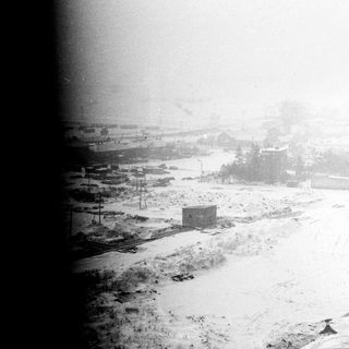 Snow-covered landscape with buildings and railway tracks.