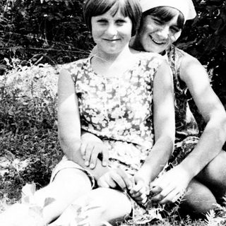 Two children sitting outside, posing for a black and white photo.