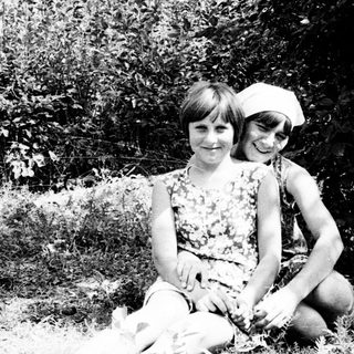 Two children sitting outside, posing for a black and white photo.