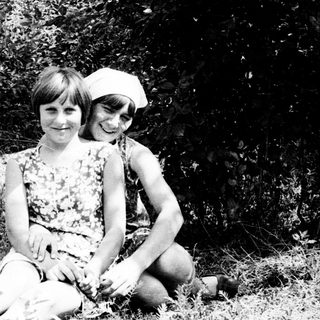 Two children sitting outside, posing for a black and white photo.