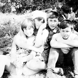 Black and white photo of a family outdoors, under a tree.