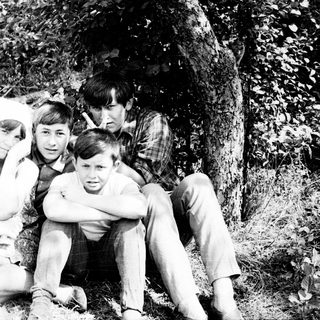 Black and white photo of a family outdoors, under a tree.