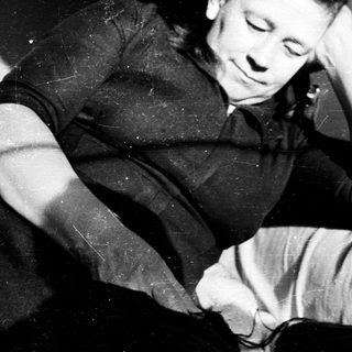 Man relaxing, resting head on knees in a chair.