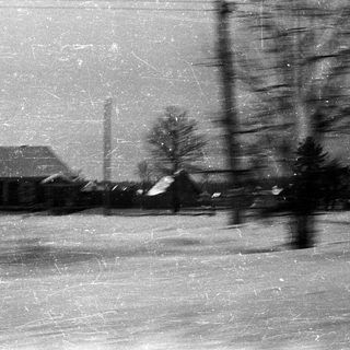 Snow-covered landscape with a building and trees.