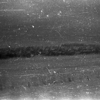 Black and white image displaying a blurred, dark vertical line.
