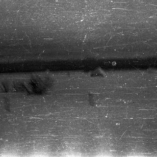 Black surface with scratches and a vertical line.