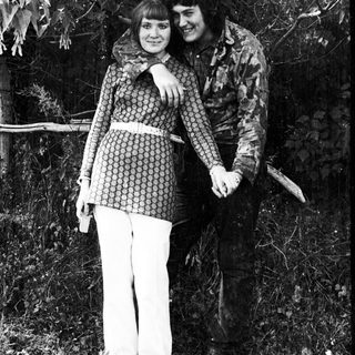 Couple poses outdoors, embracing, in a vintage style.