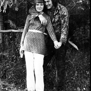 Couple poses outdoors, embracing, in a vintage style.