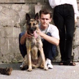Man, woman, and dog pose on stone steps.