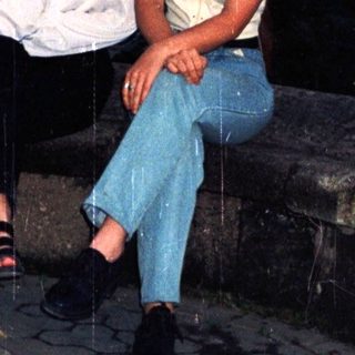 Two women sit on stone steps outdoors at dusk.