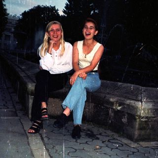 Two women sit on stone steps outdoors at dusk.