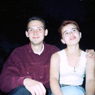 Here's a brief summary of the image: Two people sit close together, smiling at the camera.