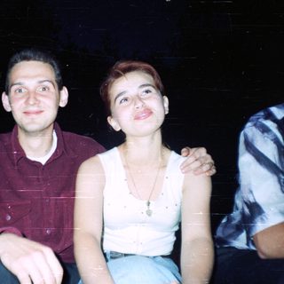 Here's a brief summary of the image: Two people sit close together, smiling at the camera.