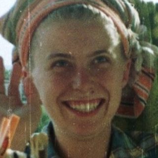 Person stands in doorway, smiling, with laundry hanging nearby.