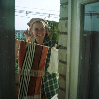 Person stands in doorway, smiling, with laundry hanging nearby.