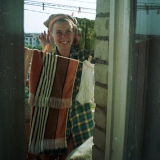 Person stands in doorway, smiling, with laundry hanging nearby.
