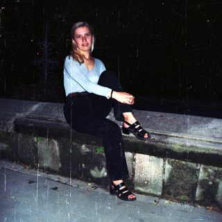 Woman sits outdoors in the rain at night.