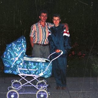 Two men stand near a stroller in the rain.