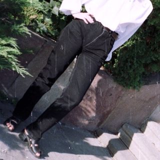 Woman in white shirt and black pants stands on stairs.