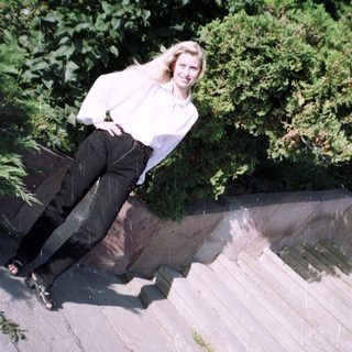 Woman in white shirt and black pants stands on stairs.