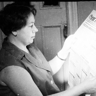 Woman reading a newspaper in a vintage, black and white photo.