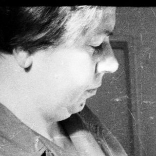Woman reading a book, seated near a door.