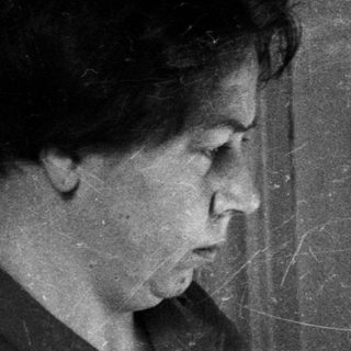 Here's a brief summary of the image: Woman reading a magazine while seated near a door.