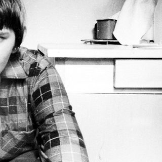 Here's a brief summary of the image: Young man in plaid shirt, looking directly at the camera.