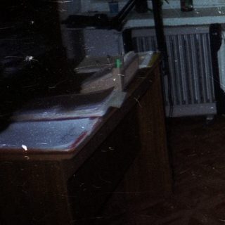 Woman sits at a vintage computer desk in a room.