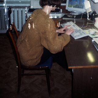 Person using an old computer at a desk.
