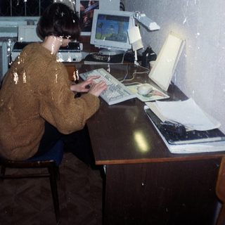 Person using an old computer at a desk.