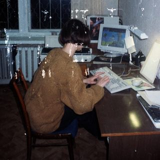Person using an old computer at a desk.