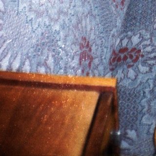 Man in suit sits on a patterned couch indoors.