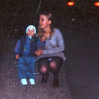 A woman and child walk down a road at night.