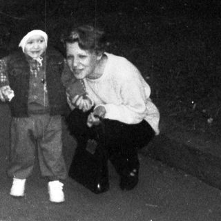 Three people, including a toddler, stand on a paved path.