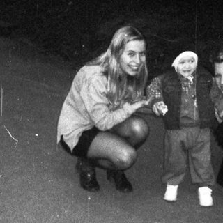 Three people, including a toddler, stand on a paved path.