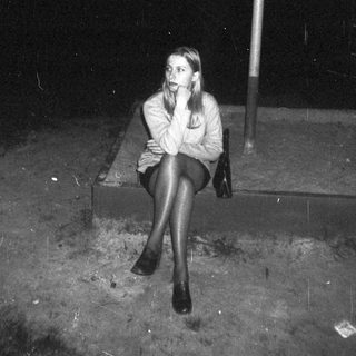 Woman sits under a shelter during a rainy night.