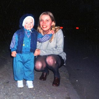 A child and woman stand on a dark road.