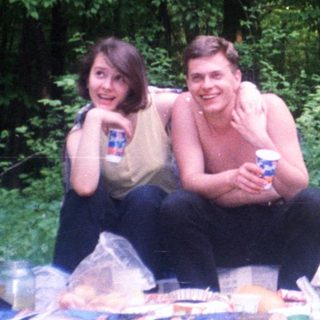 Couple relaxes outdoors with picnic and coconuts.