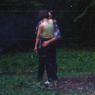 Person stands in grassy area, viewed from behind.